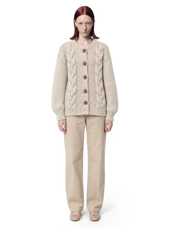 Cream cable-knit cardigan on an AI model, white wall, front