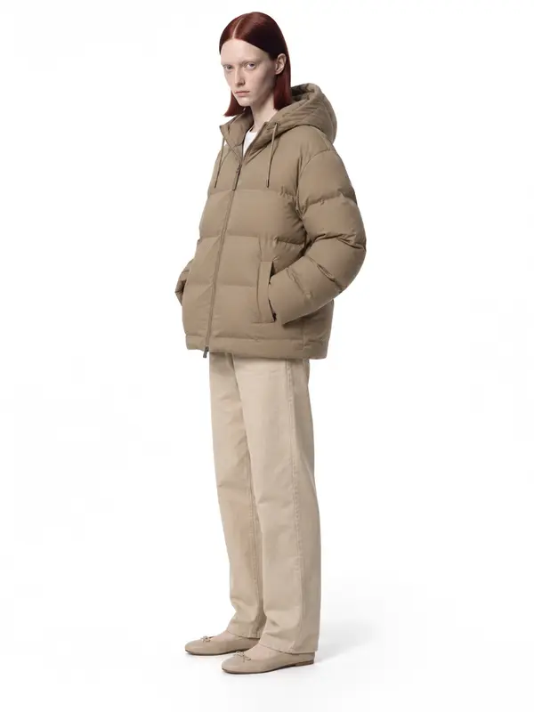 Beige puffer jacket on an AI model, white wall, three-quarter